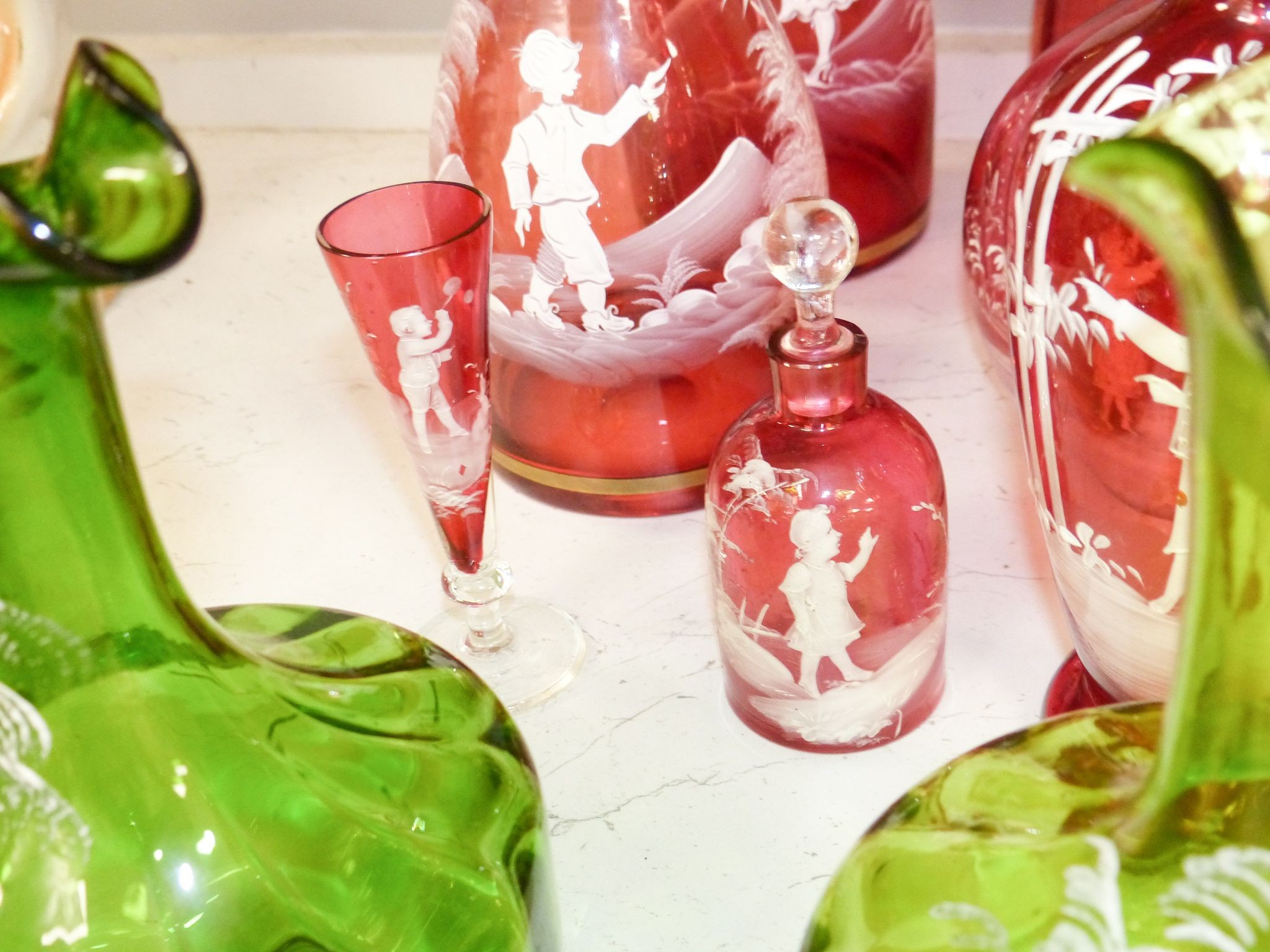 A collection of Mary Gregory cranberry and green glass decanters, jug etc (9), tallest 28.5 cm